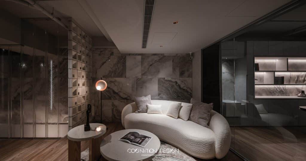 侘寂風辦公室設計，弧形沙發設計，打破方正格局感，白灰色系的辦公室裝潢搭配白色系列的沙發、茶几，讓整體呈現出一種現代簡約的風格