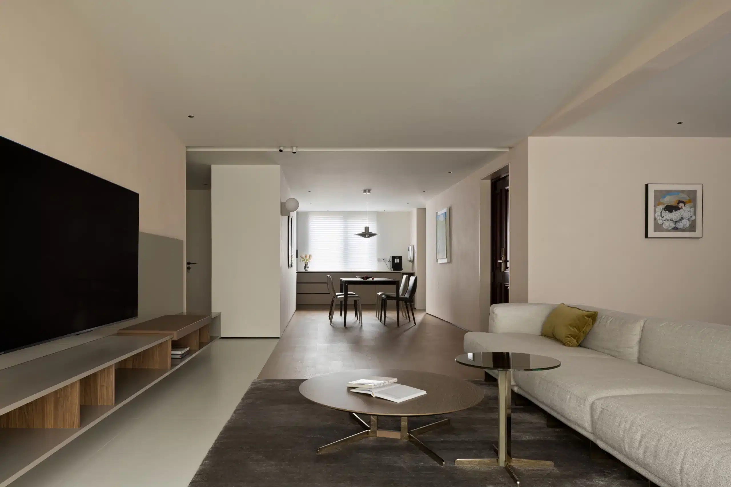 低姿態家具挑選範例：鵝卵石沙發與木質茶几，拉高天花板視覺高度比例。