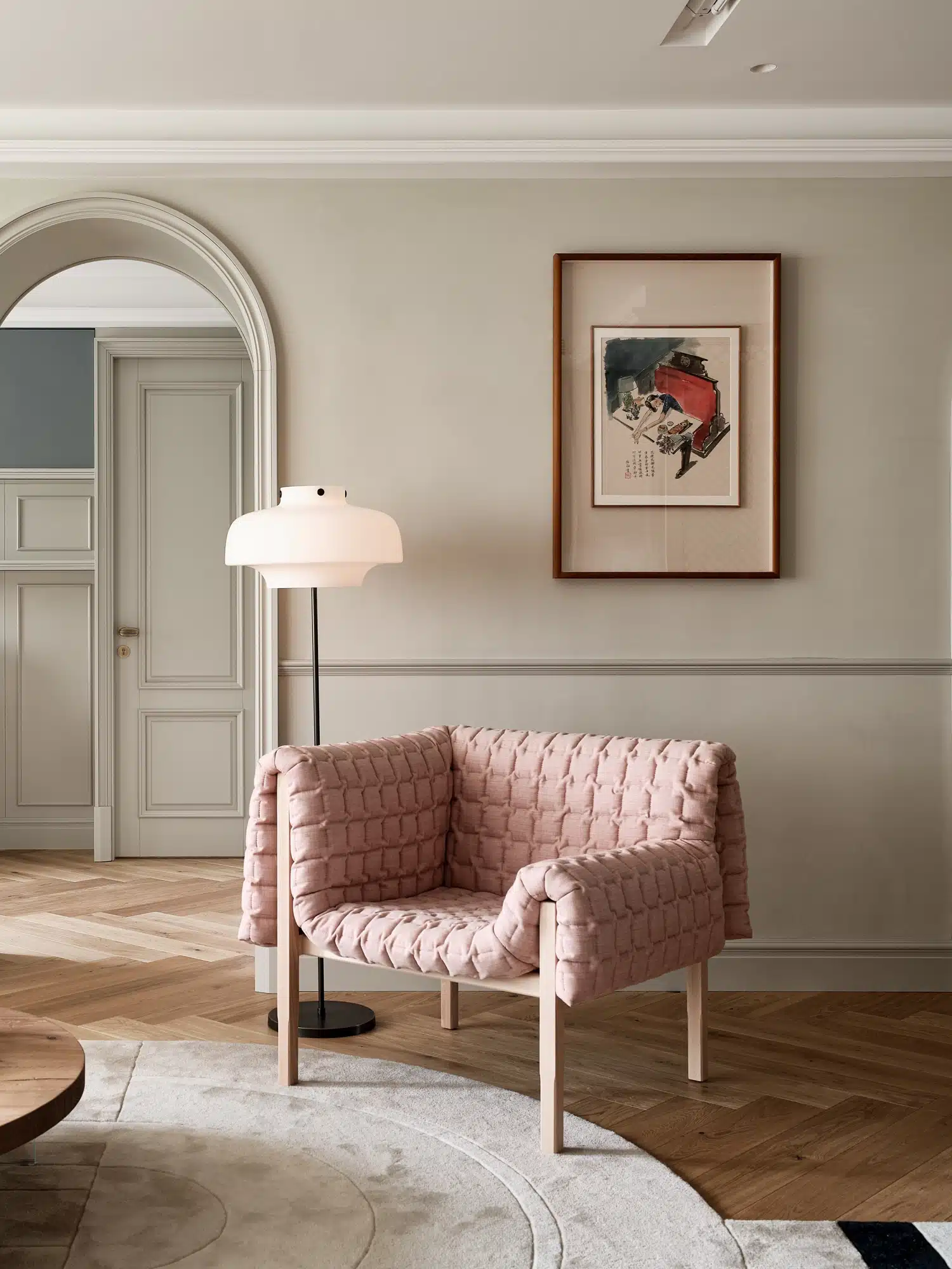 現代奶油風客廳軟裝示範,粉色絎縫設計師單椅搭配極簡落地燈、魚骨拼木地板與優雅圓弧拱門