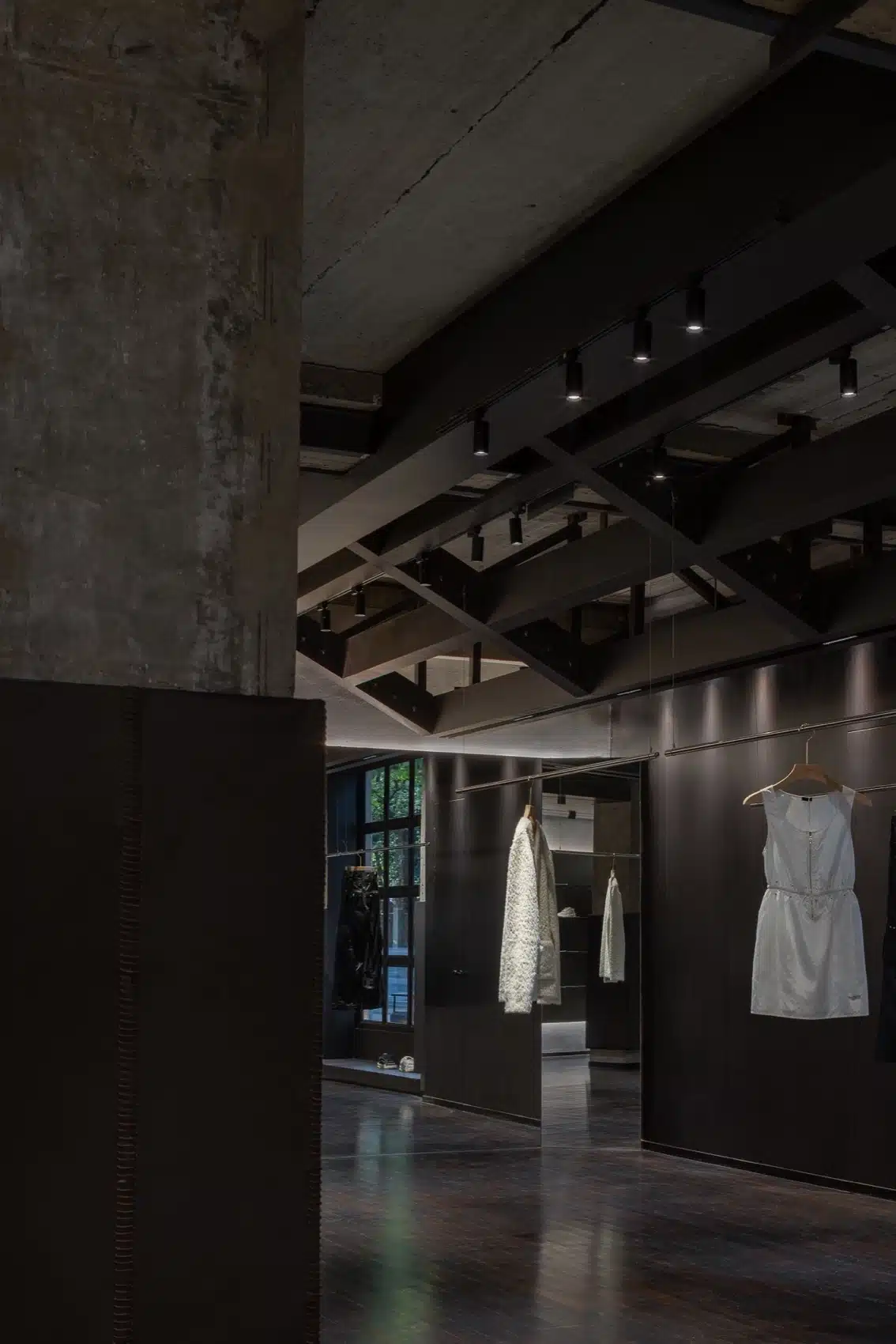 現代工業風格服飾店設計,展示裸露管線、水泥牆面與不鏽鋼陳列架。