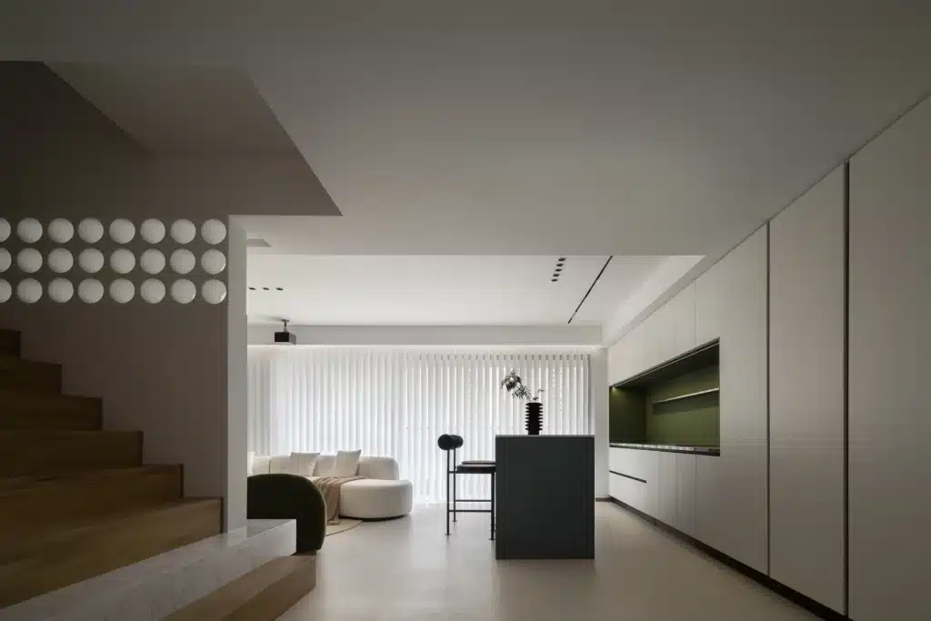 精品風客廳設計，運用具有建築感的圓形孔洞牆面作為場域區隔，搭配有機線條的白色弧形沙發與極簡投射燈光。